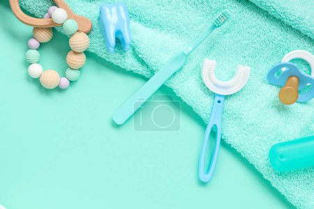 Téléchargez les photos : Serviette avec brosses à dents pour enfants, jouet et sucette sur fond turquoise - en image libre de droit