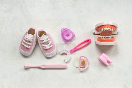 Téléchargez les photos : Brosses à dents pour enfants avec sucette, modèle à mâchoires et chaussures sur fond grunge blanc - en image libre de droit
