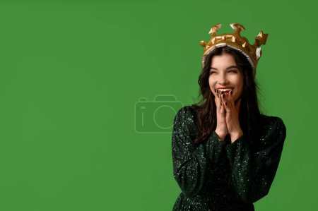 Hermosa mujer joven en vestido de fiesta elegante y corona inflable sobre fondo verde