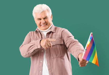 Photo for Displeased mature man pointing at LGBT flag on green background. Accusation concept - Royalty Free Image
