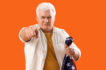 Reifer Mann mit USA-Fahne zeigt auf den Betrachter auf orangefarbenem Hintergrund. Anschuldigungskonzept