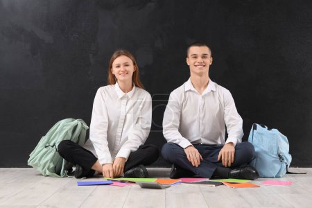 Photo for Students with copybooks and backpacks on blackboard background. End of school concept - Royalty Free Image