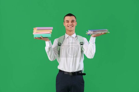 Photo for Male student with stacks of copybooks and books on green background. End of school concept - Royalty Free Image