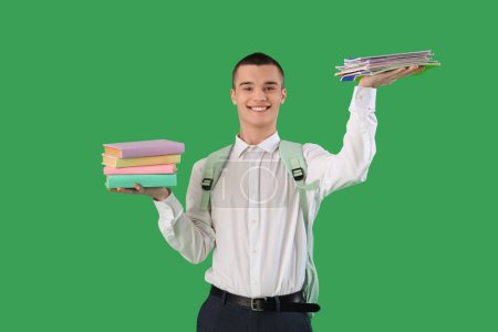 Photo for Male student with stacks of copybooks and books on green background. End of school concept - Royalty Free Image