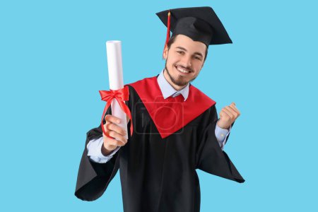 Photo for Cheerful male graduate student with diploma on blue background - Royalty Free Image