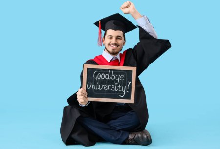 Photo for Male graduate student holding chalkboard with text GOODBYE UNIVERSITY on blue background - Royalty Free Image