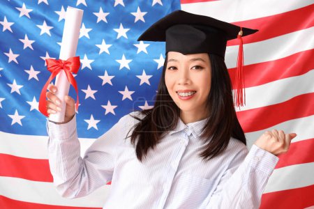 Photo for Asian female graduate student with diploma on USA flag background - Royalty Free Image