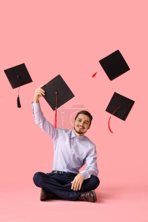 Photo for Male graduate student throwing mortar board up on pink background - Royalty Free Image