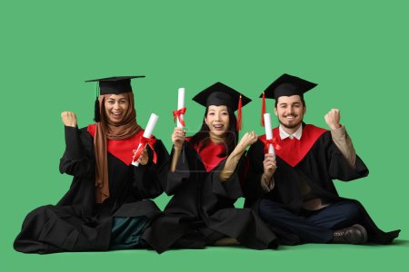Photo for Graduate students holding diplomas celebrating success on green background - Royalty Free Image