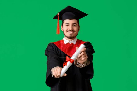 Photo for Male graduate student with diploma on green background - Royalty Free Image