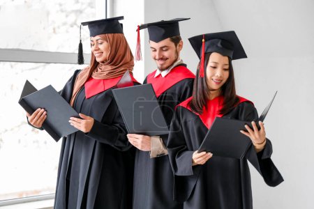 Photo for Graduate students with diplomas in light room - Royalty Free Image