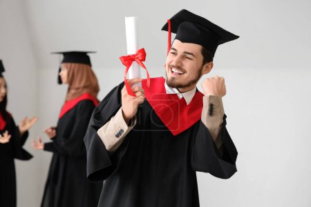 Photo for Male graduate student with diploma celebrating success in light room - Royalty Free Image