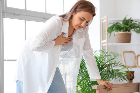 Mature woman suffering from chest pain at home. Menopause concept