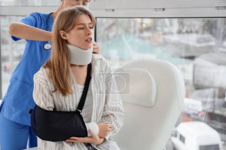Injured young woman after accident with cervical collar visiting doctor in clinic