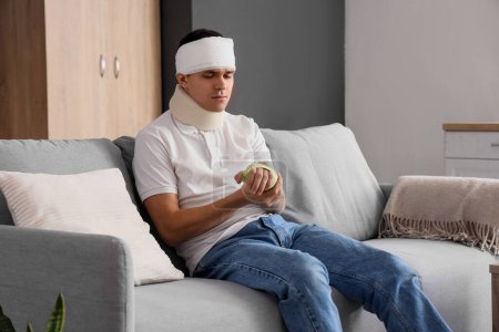 Jeune homme blessé après un accident assis sur le canapé à la maison