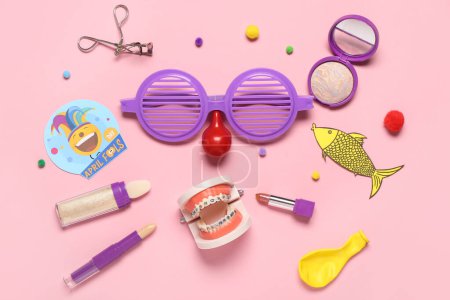 Foto de Composición con accesorios de maquillaje, modelo de mandíbula y decoración de fiesta sobre fondo rosa. Celebración del Día de los Inocentes - Imagen libre de derechos