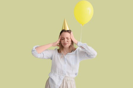 Foto de Mujer joven con resaca y globo después de la fiesta de cumpleaños sobre fondo verde - Imagen libre de derechos