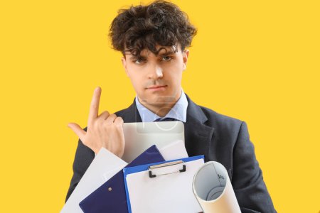 Photo for Young businessman with documents showing loser gesture on yellow background - Royalty Free Image