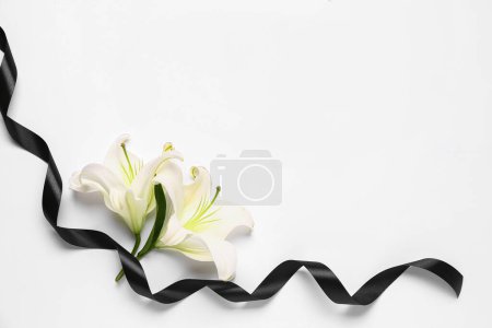 Frame made of beautiful lily flowers with black funeral ribbon on white background