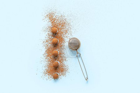 Leckere Schokoladentrüffel und Metalltee-Ei auf blauem Hintergrund