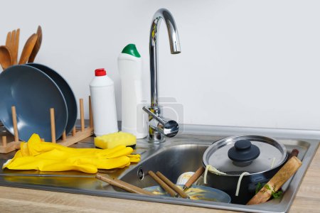 Dirty dishes in sink near white wall