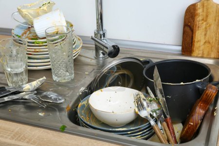 Dirty dishes in sink near white wall