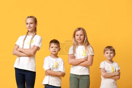 Téléchargez les photos : Groupe d'enfants avec des rubans jaunes sur fond de couleur. Journée internationale du cancer chez les enfants - en image libre de droit