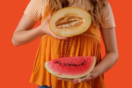 Beautiful young woman with fresh watermelon and melon on orange background