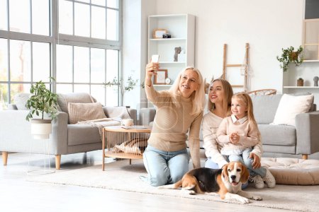 Famille heureuse avec chien mignon prenant selfie à la maison