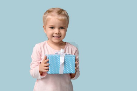 Linda niña feliz con caja de regalo sobre fondo azul. Hanukkah celebración