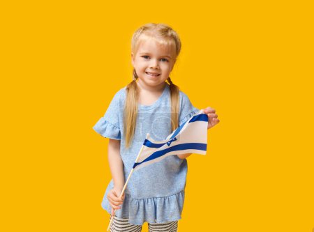 Jolie petite fille heureuse avec le drapeau d'Israël sur fond jaune. Hanoukka célébration