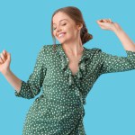 Beautiful young happy woman dancing on blue background