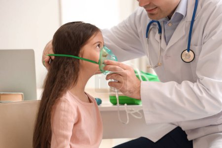 Téléchargez les photos : Petite fille avec médecin utilisant nébuliseur à la clinique - en image libre de droit