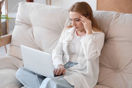 Mature woman with laptop experiencing menopause at home
