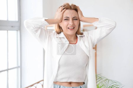 Mujer madura estresada que experimenta la menopausia en casa