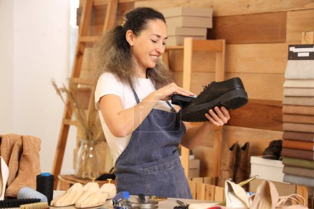 Female shoemaker polishing leather boot in workshop