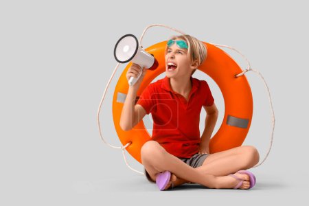 Photo for Little boy lifeguard with ring buoy on grey background - Royalty Free Image