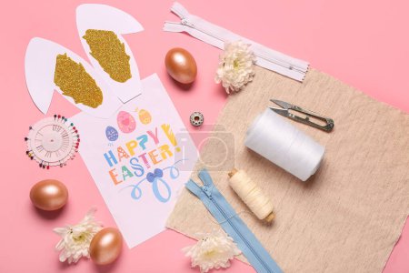Foto de Composición con tarjeta de felicitación, artículos de costura y decoración de Pascua sobre fondo rosa - Imagen libre de derechos