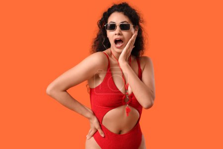 Photo for Beautiful young shocked African-American female lifeguard on orange background - Royalty Free Image