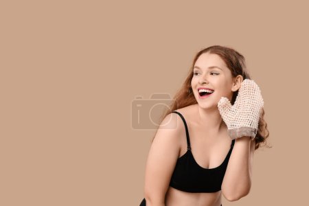 Schöne junge glückliche Frau mit Badehandschuh auf braunem Hintergrund