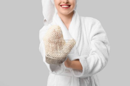 Schöne junge glückliche Frau im Bademantel mit Badehandschuh auf grauem Hintergrund, Nahaufnahme