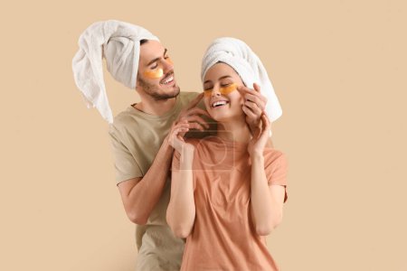Young loving couple after shower with under-eye patches on beige background