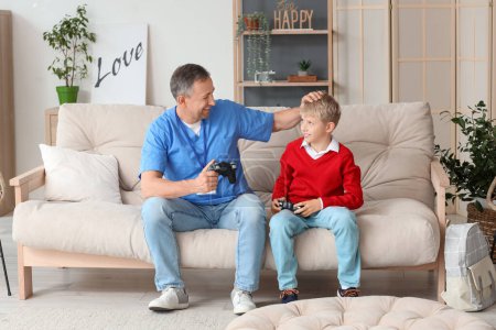 Photo for Mature doctor with his little son playing video game at home - Royalty Free Image