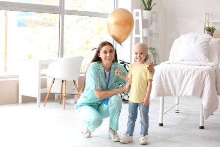 Téléchargez les photos : Petite fille après chimiothérapie avec ballon doré et infirmière en clinique - en image libre de droit