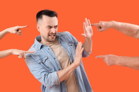 Photo for People pointing at young man on orange background. Accusation concept - Royalty Free Image