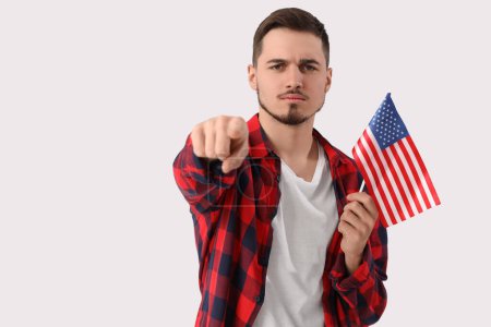 Junger Mann mit USA-Fahne zeigt auf den Betrachter auf weißem Hintergrund. Anschuldigungskonzept