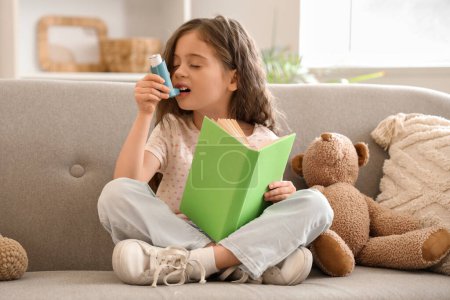 Téléchargez les photos : Petite fille avec livre utilisant inhalateur à la maison - en image libre de droit