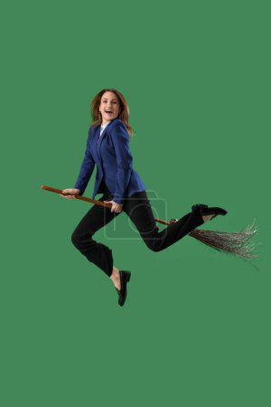 Femme d'affaires drôle avec balai de sorcière volant sur fond vert