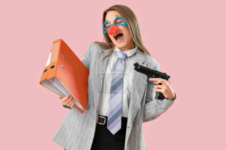 Foto de Joven mujer de negocios en disfraz divertido con carpetas y pistola sobre fondo rosa - Imagen libre de derechos