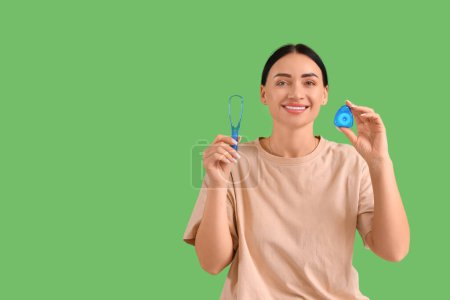 Téléchargez les photos : Belle jeune femme heureuse avec fil dentaire et grattoir de langue sur fond vert - en image libre de droit